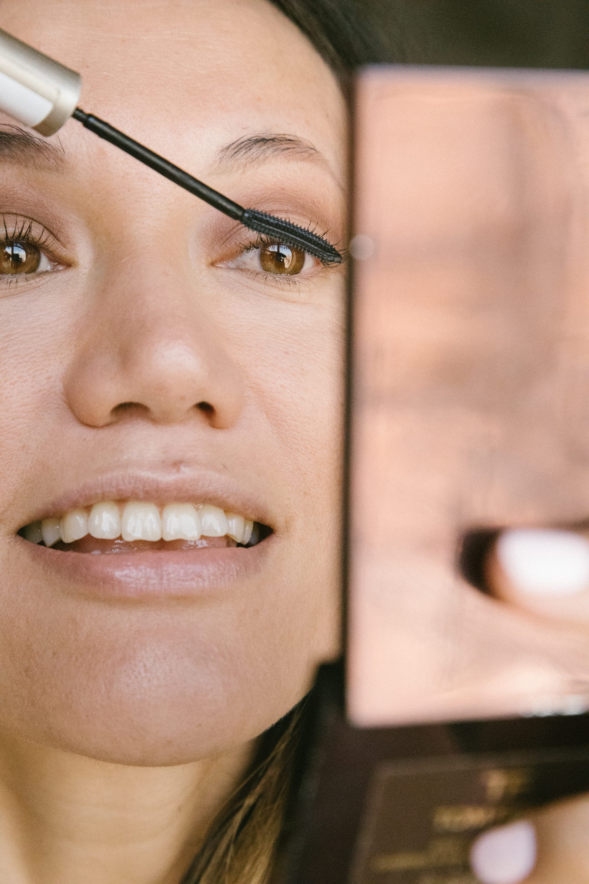 Girl putting on keratin mascara with a mirror